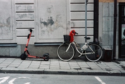 红黑相间的自行车，白墙边有训练轮